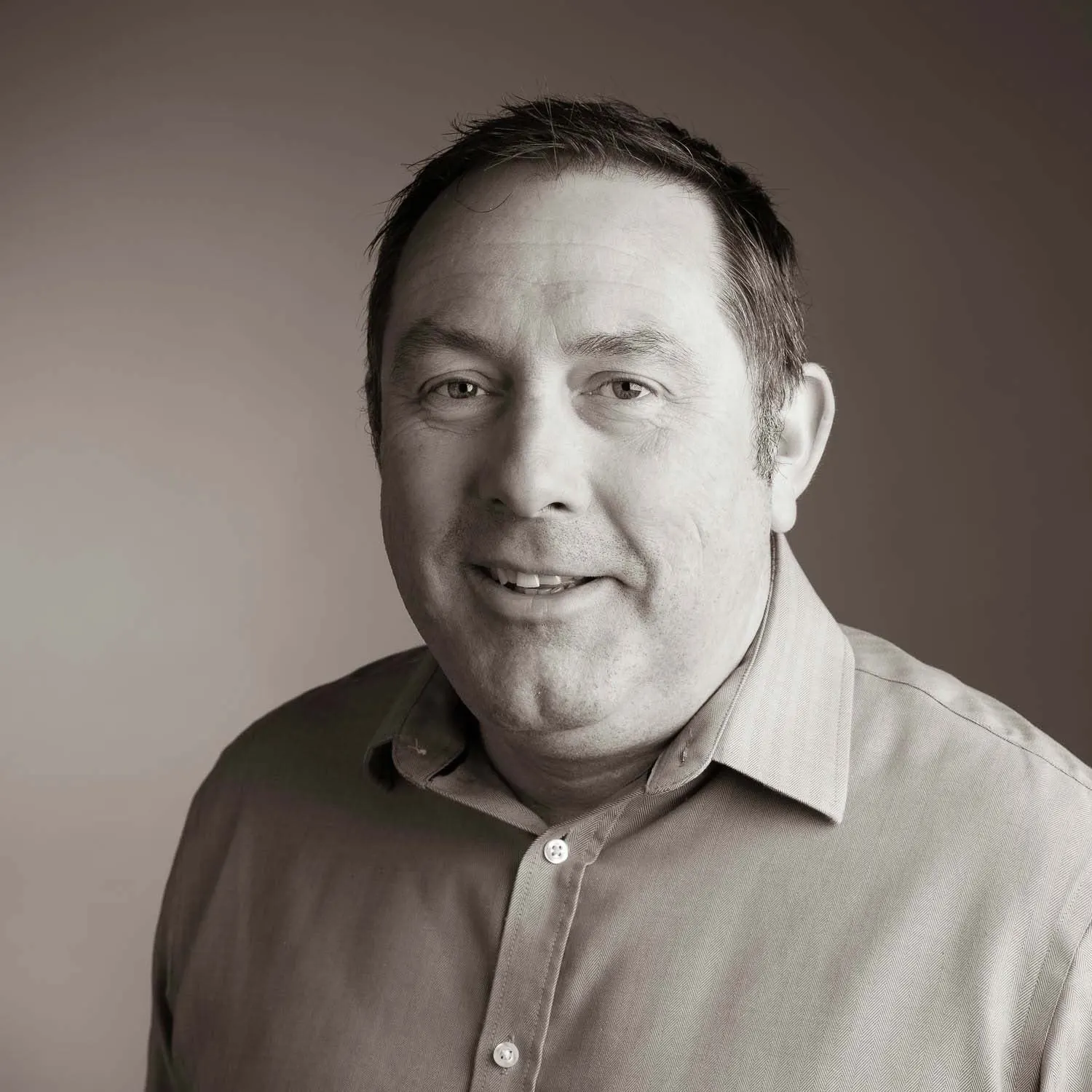 Black and white business headshot against a grey backdrop