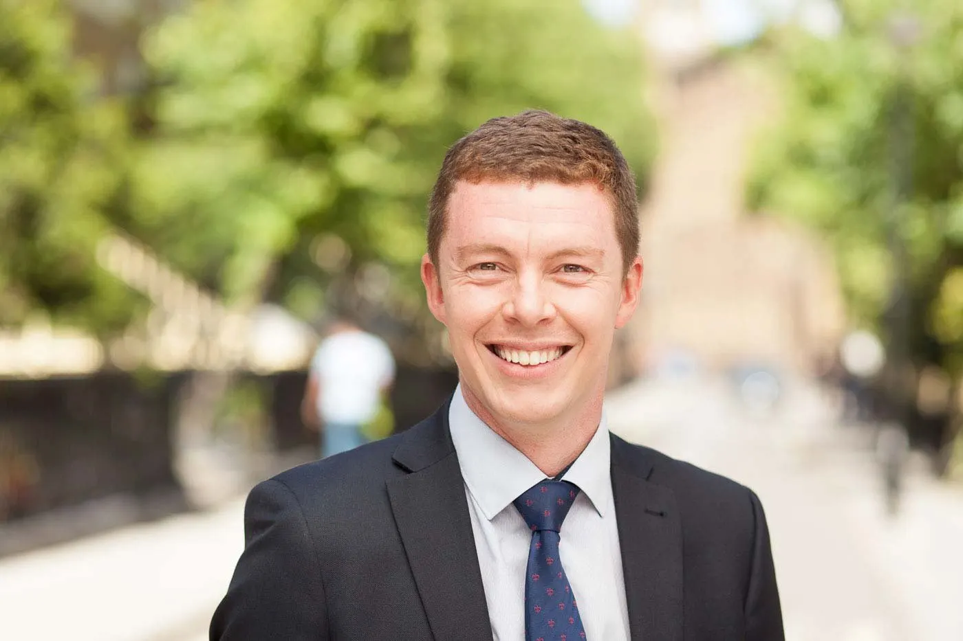 Smiling businessman in a suit and red tie, photographed outdoors in London
