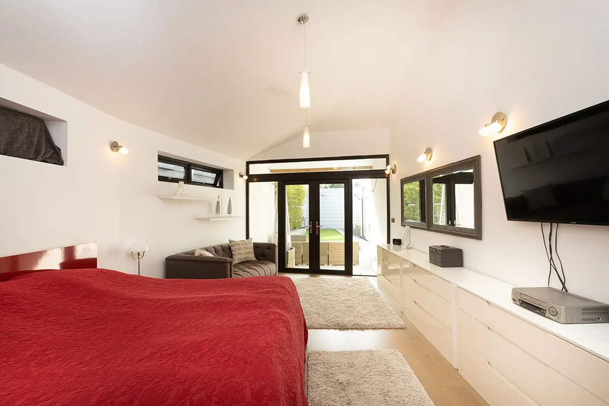 Bedroom with a red bedspread under a vaulted ceiling
