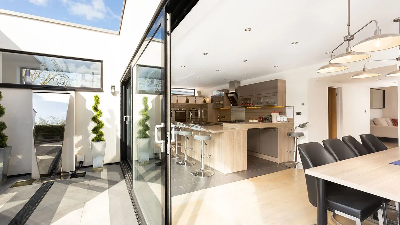 Kitchen and dining area under a skylight, with glass doors to the garden