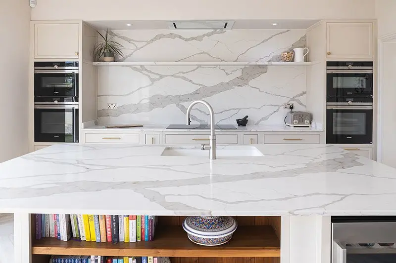 The kitchen from the doorway: marble island, sink and a wall of ovens