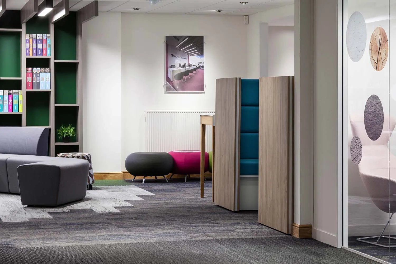 Office meeting booths with green shelving and soft seating