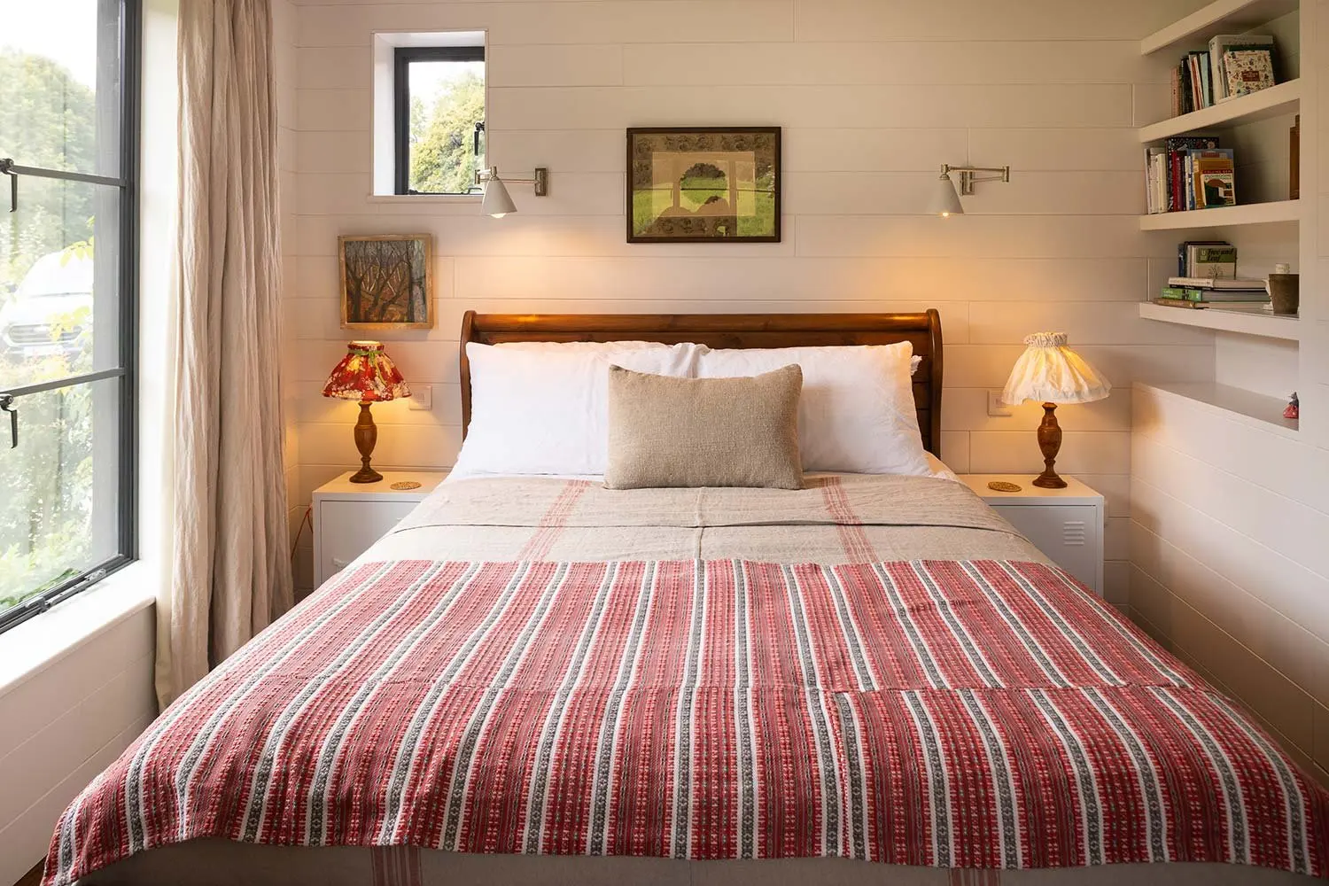 Bedroom with a striped bedspread and the lamps lit