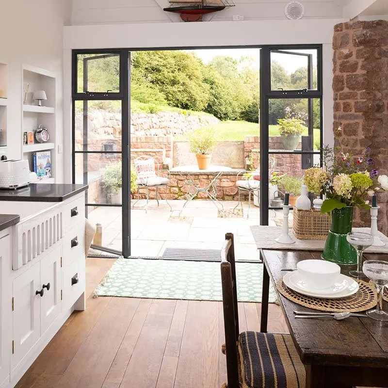 Cabin kitchen with French doors open onto a garden